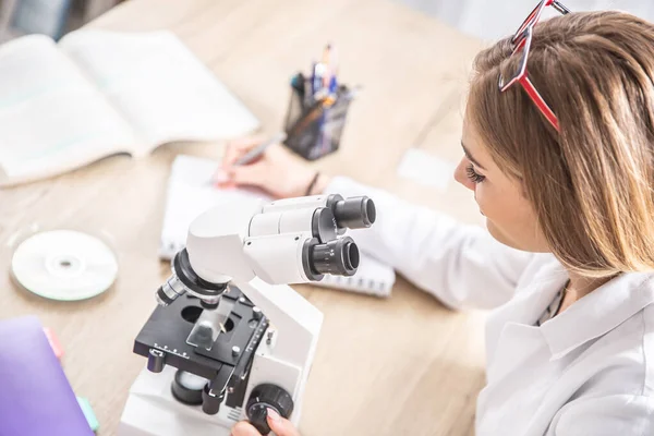 Tecnico Laboratorio Femminile Che Annota Osservazioni Del Lavoro Con Microscopio — Foto Stock