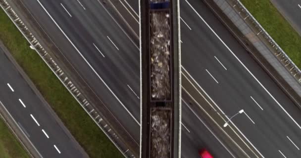 Overhead skott av ett godståg som passerar järnvägen på en bro över en motorväg — Stockvideo