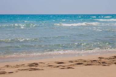 Beyaz dalgalar ve kum ayak izleri ile mavi denize sıfır