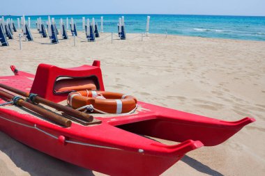 Kırmızı can kurtaran sandalı mavi gökyüzü güneşli bir yaz bulutlarda ile karşı kumlu bir plaj üzerinde turistler için. İnsanlar olmadan şezlonglar ile plaj. Emanet turist