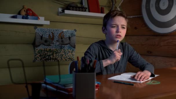 Thuis aan het studeren. De jongen doet zijn huiswerk in zijn eentje. Camera glijden. — Stockvideo