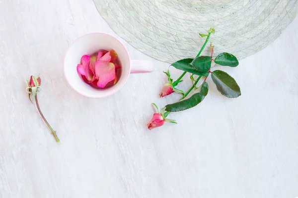 Tazza da tè rosa con petali di rosa su sfondo chiaro con boccioli di rosa — Foto Stock