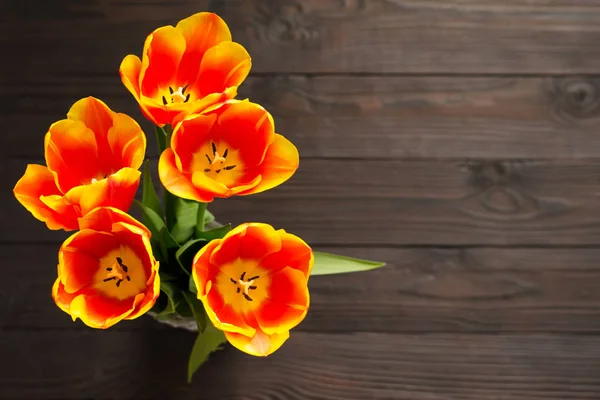 Bukiet czerwonych i żółtych tulipanów na ciemnym tle drewnianych. Widok z góry. Miejsce — Zdjęcie stockowe