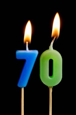 Siyah arka plan üzerine izole kek için yetmiş rakamlar (sayılar, tarihler) şeklinde mum yakma. Bir doğum günü, yıldönümü, önemli bir tarih, tatil, sofra, kek kutlama kavramı 