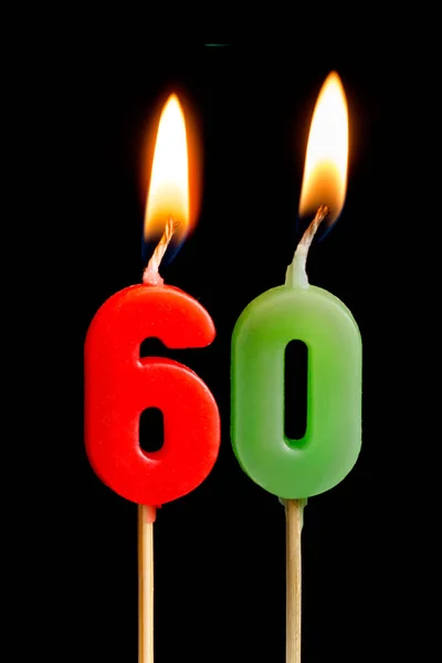 Горящие свечи в виде шестидесяти фигурок (чисел, дат) для торта изолированы на черном фоне. Концепция празднования дня рождения, юбилея, важной даты, праздника, сервировки стола, торта — стоковое фото