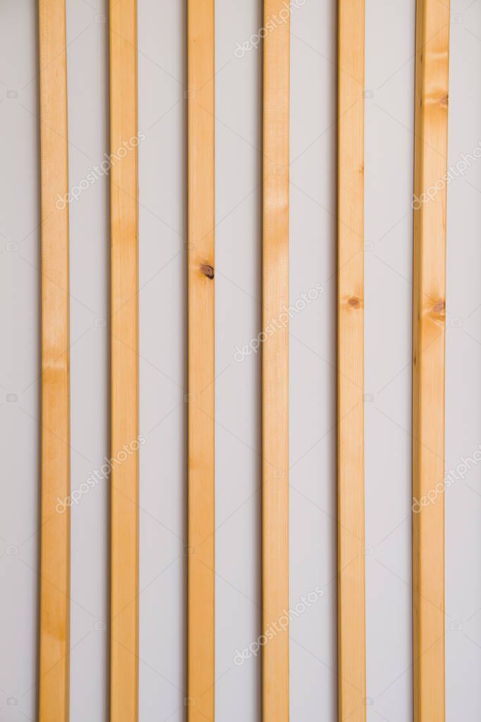 Wooden vertical slats batten on a light gray wall background. Interior