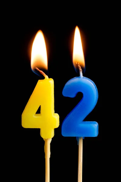 Burning candles in the form of 42 forty two (numbers, dates) for cake isolated on black background. The concept of celebrating a birthday, anniversary, important date, holiday, table setting — Stock Photo, Image