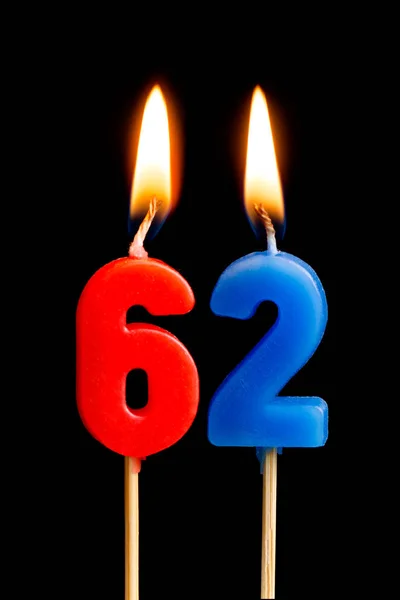 Burning candles in the form of 62 sixty two (numbers, dates) for cake isolated on black background. The concept of celebrating a birthday, anniversary, important date, holiday, table setting