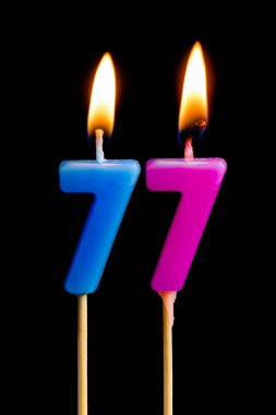 77 yetmiş yedi şeklinde mum yakma (sayılar, tarihler) siyah arka plan üzerine izole kek için. Kutluyor doğum günü, yıldönümü, önemli bir tarih, tatil, Tablo ayarı kavramı