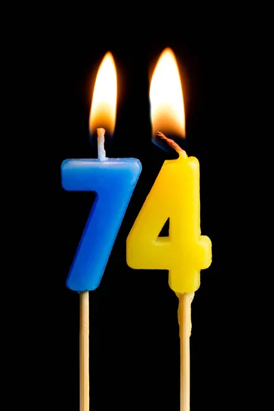 Burning candles in the form of 74 seventy four (numbers, dates) for cake isolated on black background. The concept of celebrating a birthday, anniversary, important date, holiday, table setting — Stock Photo, Image