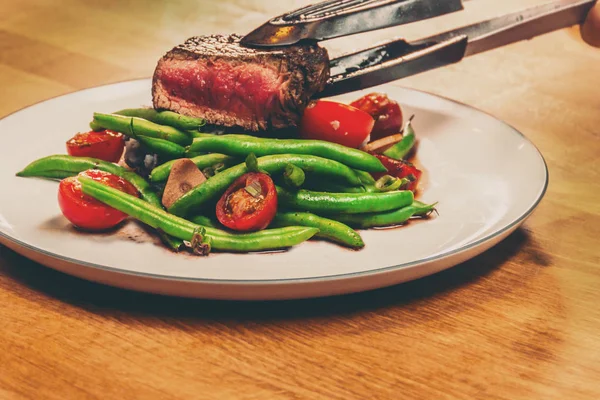 Metal Pliers Serving Cooked Steak Royalty Free Stock Photos