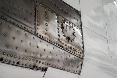 Doku yüzeyi eski bir uçak. Boyalı alüminyum ve paslanmaz çelik perçin ile. Seçici odak.