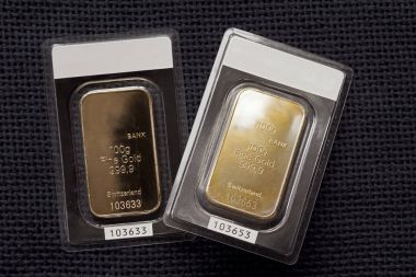 İki altın külçelerini 100 gram her arka planı koyu kumaş doku basılan. 