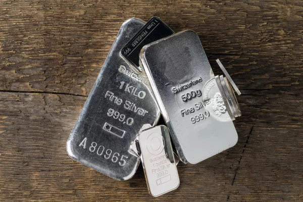 Silver bullion on wood texture background. Coins and bars.