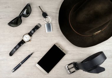 Smartphone, keçe şapka, kol saati, deri kemer ve diğer erkek aksesuarlar ağartılmış meşe bir doku ile yüzeyi.