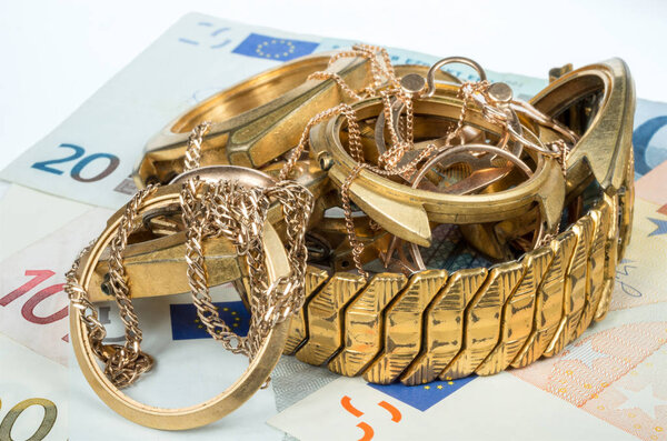 A scrap of gold. Old and broken jewelry, watches of gold and gold plated on a background of Euro banknotes