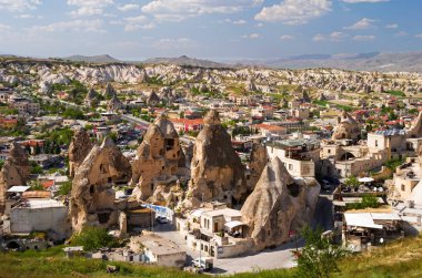 Goreme, Kapadokya, Türkiye 24 Nisan 2018 Gün batımından önce ön planda kumtaşı oluşumlarıyla köy manzarası.