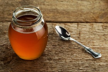 Yuvarlak cam kavanoz, ahşap arkaplan dokusunda taze tereyağı ve kaşık.