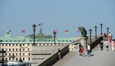 Stockholm, İsveç 7 Haziran 2019. Kent sakinleri ve turistler, Finlandiya, Norveç, İsveç, Danimarka, Almanya ve Uk 'un bayraklarıyla Grand Hotel' in arka planında Kraliyet Sarayı yakınlarında yürürler. Seçici odak.