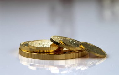 Gri bir arka planda çeşitli boyutlarda altın para yığını.