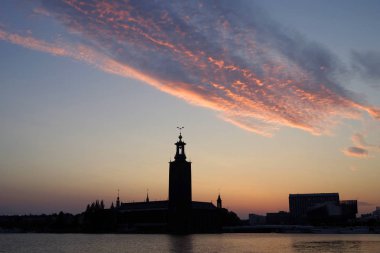 Gün batımında belediye binasının silueti gökyüzüne karşı. Stockholm, İsveç.