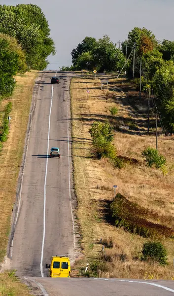 丘陵地の木々に囲まれたアスファルトの道路上の車 選択的焦点 — ストック写真
