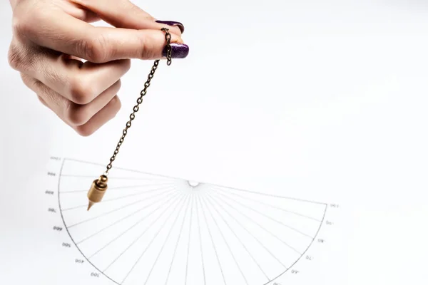 Arm of dowser with hand-held pendulum over the chart. Selective focus. 