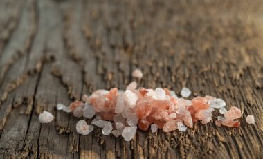 Sert ahşap bir yüzey üzerinde pembe Himalaya tuzu kristalleri.