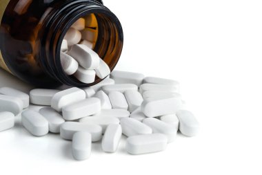 White oval pills with a dark glass bottle. isolated on a white background. 