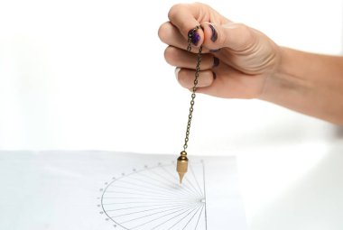 Arm of dowser with hand-held pendulum over the chart. Selective focus.