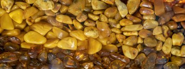 Çeşitli şekil ve renklerdeki kehribar taşlarının panoramik arkaplanı.