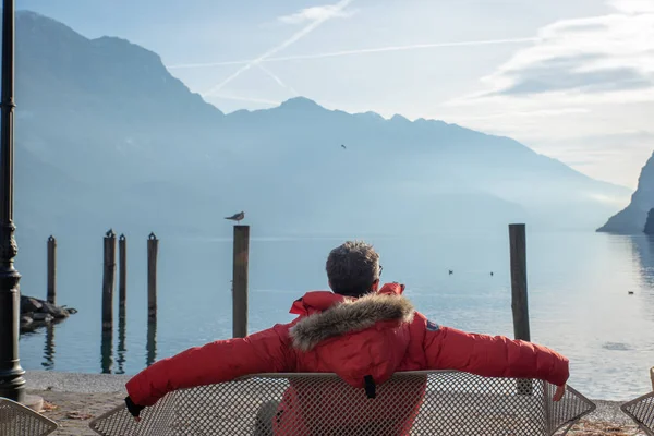 Homem relaxante em um banco admira a vista do Lago de Garda — Fotografia de Stock