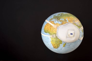 Maskeli Dünya gezegeni. Koronavirüse karşı savaş ve önleme. COVID-19 önleme, kirlilik ve iklim değişikliği kavramı. Ön planda Avrupa, Afrika ve Asya. Siyah arkaplan