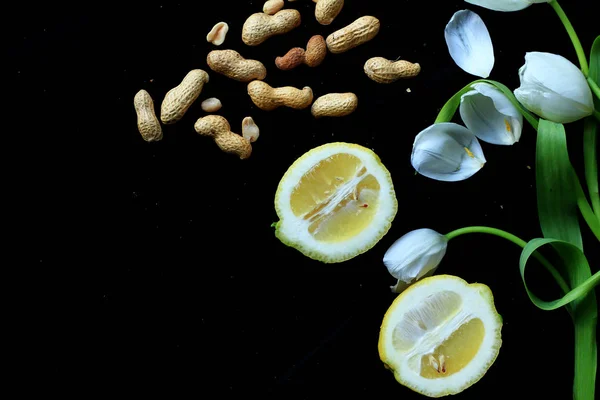 lemons, nuts and flowers on black background
