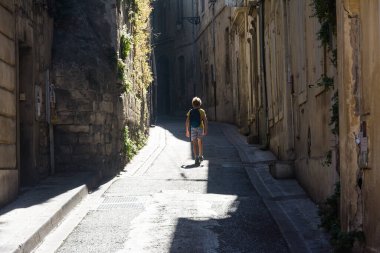 Arles, Fransa-Ağustos 14. 2016: Güneşli bir günde Arles 'in dar sokaklarında sırt çantasıyla gezen tanınmayan bir çocuk