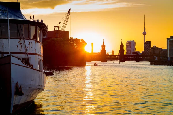 De skyline van de Berlijn met oude schip wrak in de Spree rivier bij zonsondergang, Duitsland — Stockfoto