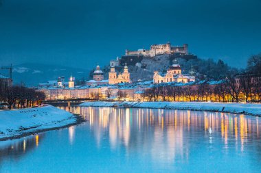 Ünlü Festung Hohensalzburg ve Salzach nehri ile tarihi Salzburg şehrinin klasik manzarası. Kış aylarında güzel bir alacakaranlıkla aydınlanıyor. Salzburger Diyarı, Avusturya.