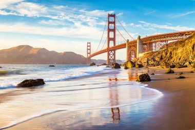 Classic panoramic view of famous Golden Gate Bridge seen from scenic Baker Beach in beautiful golden evening light on a sunny day with blue sky and clouds in summer, San Francisco, California, USA clipart