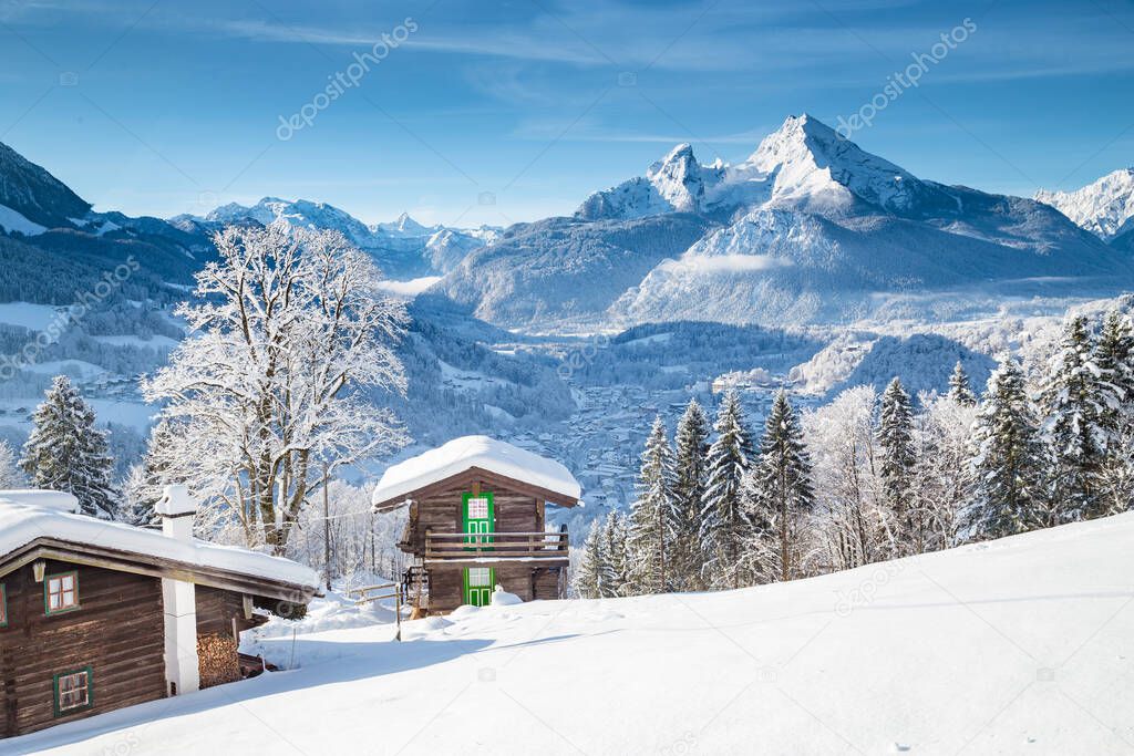 Beautiful view of traditional wooden mountain cabins in scenic winter wonderland mountain scenery in the Alps