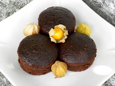 Beyaz tabakta çikolatalı kekler ve bitki özü.