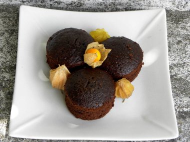 Beyaz tabakta çikolatalı kekler ve bitki özü.