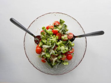                      Brokoli ve vişneli domates salatası beyaz arka planda bir kasede          