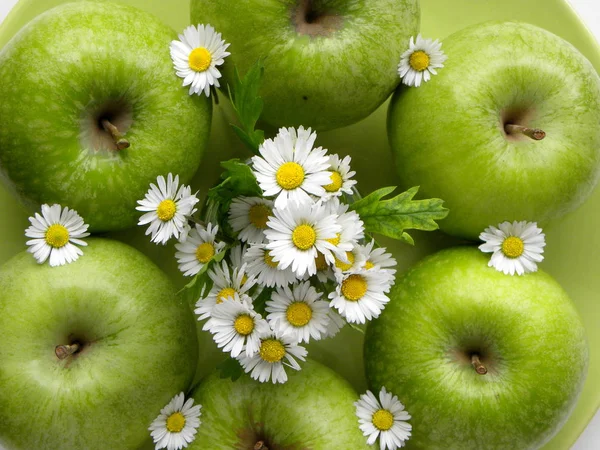 green apples and a bouquet of daisies close-up