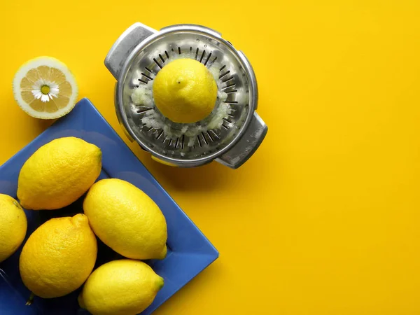 Limões Maduros Uma Placa Azul Espremedor Aço Manual Fundo Amarelo — Fotografia de Stock