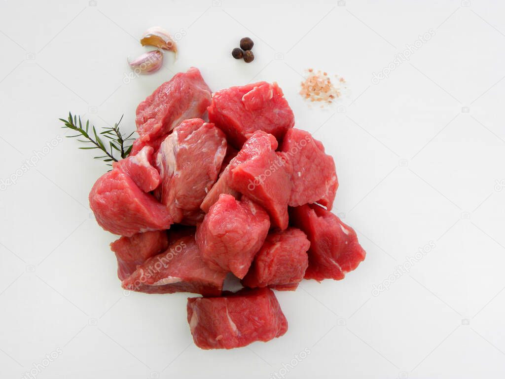           Large pieces of fresh beef and spices on a white background. Large pieces of red meat.                     