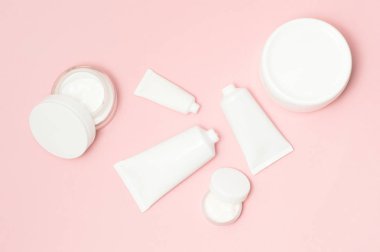 Beyaz kozmetik tüpler ve pembe bir arka plan üzerinde krem kapları Üstten Görünüm