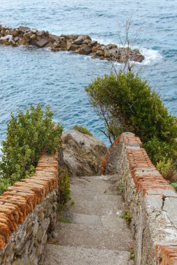 old stairs and beautiful seascape with stones in Riomaggiore, Italy clipart