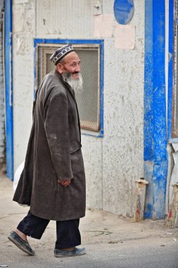 Hotan, Çin-3 Ekim 2017: Uygurlar çoğunlukla Uygur Özerk Bölgesi 'nde yaşayan bir Türk halkıdır. Uzun gri sakallı yaşlı adam pazar yerinde bir sokakta yürüyor..