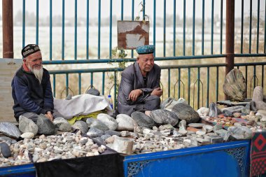 Hotan, Xinjiang, Çin-4 Ekim 2017: Uygur satıcıları, Yurungkax nehri yakınlarındaki bir pazarda müşterileri beklerken yeşim taşı ve diğer mineralleri satıyorlar..