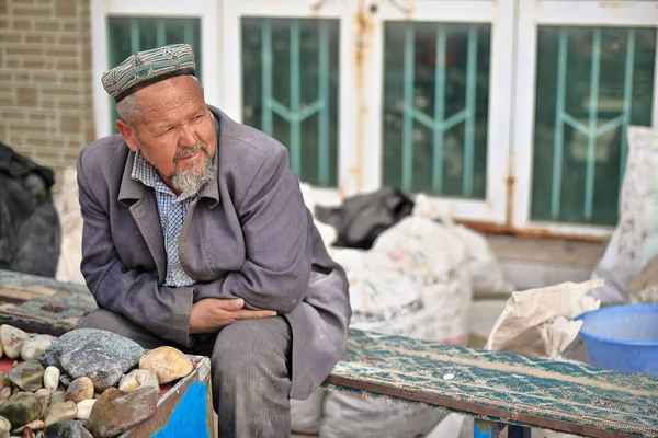 中国新疆和田 2017年10月4日 维吾尔族供应商在玉树市附近的一个市场摊位上出售玉石和其他矿产品 他们坐在玉龙江边的长椅上等待顾客 — 图库照片